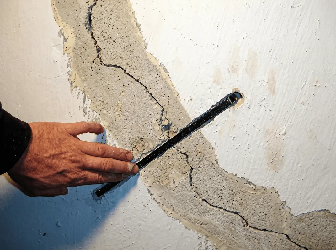 A wall with a large crack is being inspected by a professional in Lincoln, NE